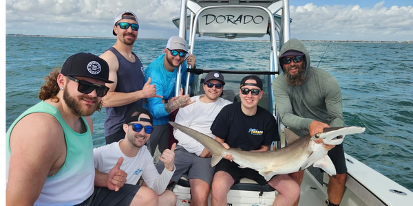 Clients holding a hammerhead shark caught on a shark fishing charter in New Smyrna Beach, Florida