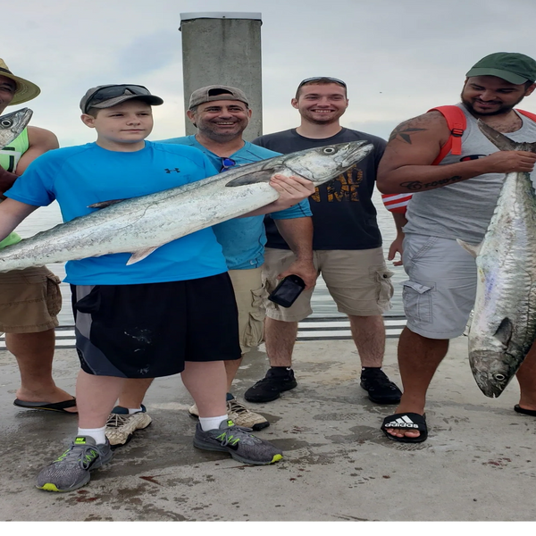 Group of clients holding kingfish caught deep sea fishing in New Smyrna Beach